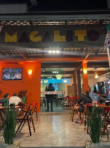 Fachada e mesas externas do Restaurante Magalito em João Monlevade com iluminação acolhedora à noite
